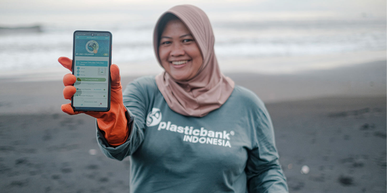 A woman showing Plastic Bank app at the beach