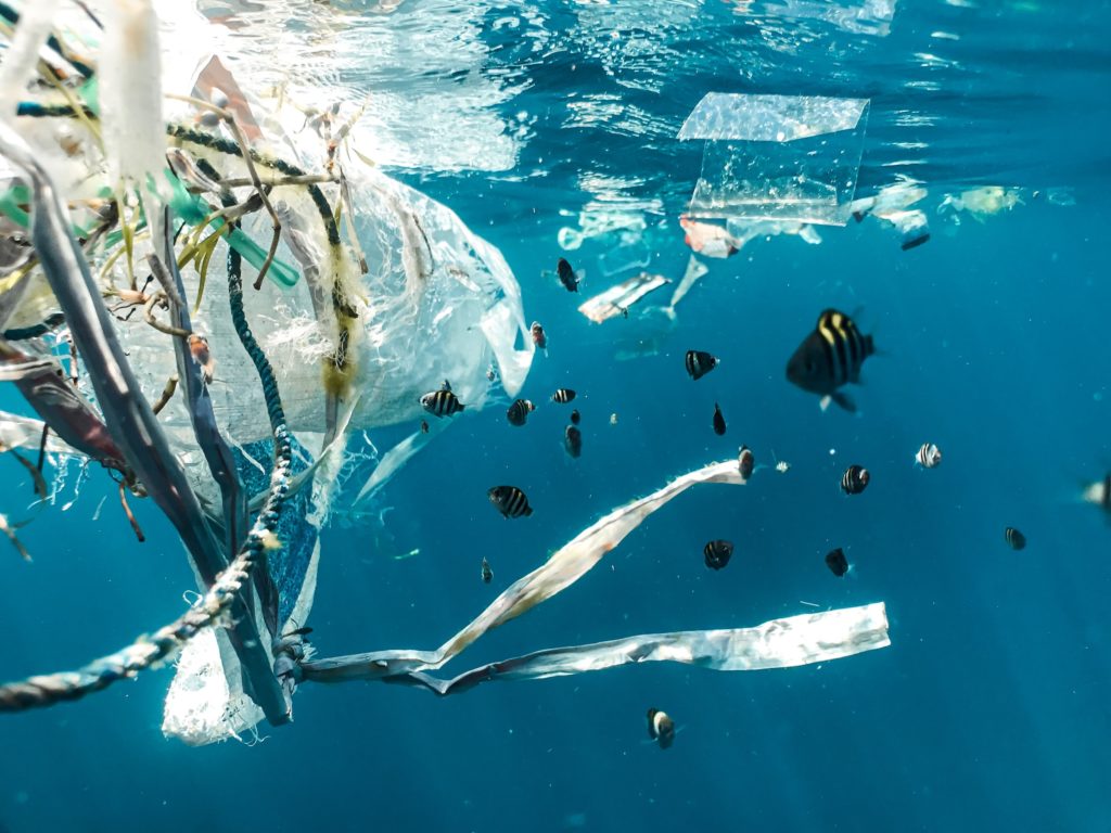 Plastic waste in the ocean with fish swimming around it